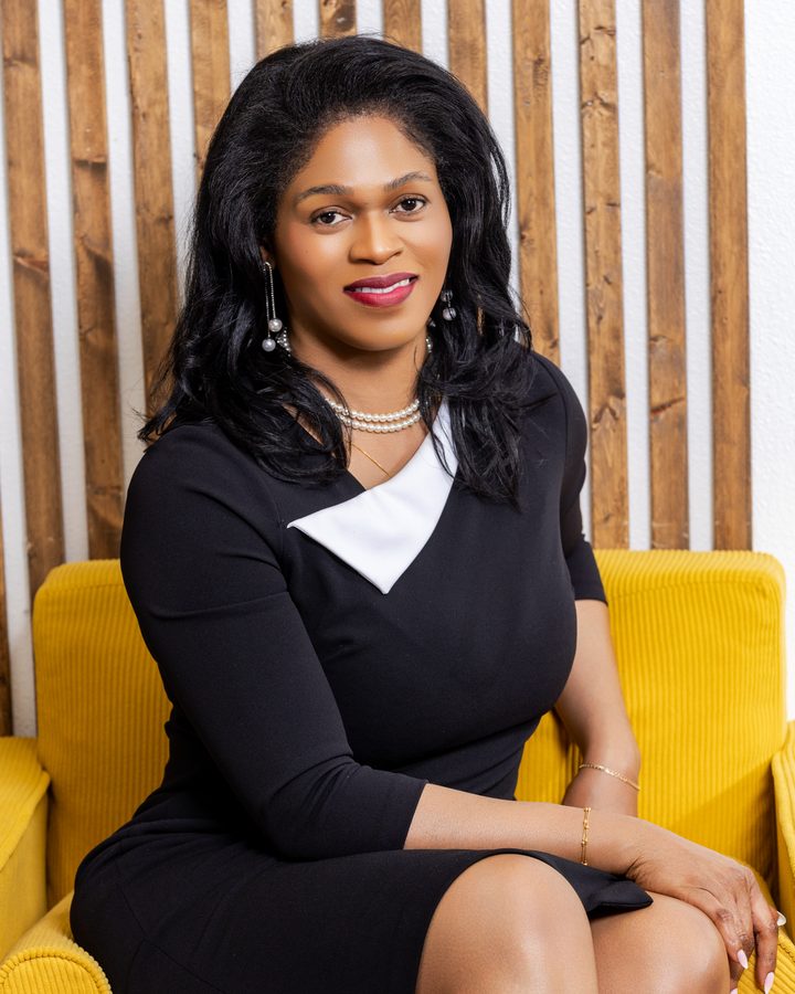 Blanche Kalala smiling, seated in a yellow armchair